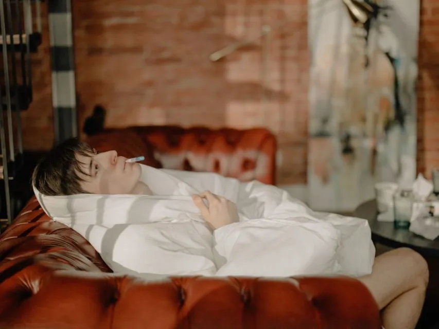 Mitos Tentang Demam yang Masih Dipercaya Banyak Orang 10 Men with white blanket dan termometer in his mouth